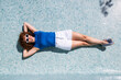 © VISTA by Westend61 - Relaxing model in an empty blue tiled swimming pool in Granada Spain