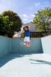 © VISTA by Westend61 - Model jumping mid-air in an empty swimming pool during summer