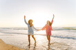 © maxbelchenko - Two happy girlfriends are having fun on the seashore in the rays of the sunset. A young woman is relaxing and enjoying the seascape. Concept of friendship, fun, and nature.