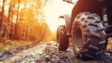 Close-up of muddy ATV tires on a forest dirt road at sunset