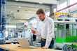 © BusinessClass by W61 - Manager reviewing documents by laptop in production hall