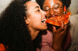 © DisobeyArt - Hungry african american girls eating pizza outdoor in the streets after party concert - Food, people lifestyle  and nightlife concept - Main focus on left woman mouth - UGC flash content