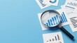 © Masque - A magnifying glass hovers over financial reports and charts for business analysis.