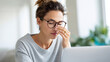 © Jane_S - Young woman rubbing nose while working at home desk