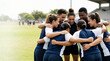 © Xenia - Diverse sports team in a huddle on grassy field. Happy male and female athletes with arms around each other showing unity and teamwork. Copy space for text