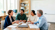 © Xenia - Diverse team of teachers having a discussion around a table in a classroom. Professional educators collaborating and planning strategy
