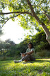 © Wavebreak Media - African American man sitting in park wearing T-shirt holding tablet with folio nearby, copy space