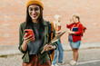 © La Famiglia - Smiling student using mobile phone on campus