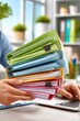 © Georgii - Business paperwork and colorful file folders held over a laptop in a modern office
