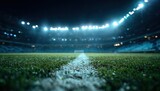 Low angle view of a vibrant green grass soccer field with a white line under bright stadium lights at night, creating a dramatic and atmospheric sports arena scene.