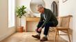 © Nataliia - Elderly man sitting on bench while tying his shoes in a hallway