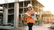 © bayu - Female construction engineer in a white hard hat and orange safety vest reviewing blueprints and a digital tablet on an active building site during golden hour