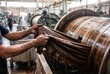 © Stitch - Factory worker handling wet brown hides next to large rotating wooden drums in a leather tannery