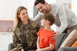 © New Africa - Woman in military uniform spending time with her family on sofa at home