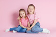 © New Africa - Happy little sisters posing on pink background