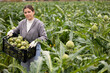 © JackF - Portrait of positive farmer girl holding a box of ripe artichokes