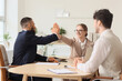 © Pixel-Shot - Female business mediator giving high-five to client at table in office