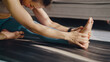 © WARAPHON - Woman stretches her foot gently on yoga mat. Her posture shows calm focus and mild concentration. Soft light casts gentle shadows across the mat. Ideal for health, wellness, or fitness-related content