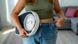 © PNG shops - Woman holding scale showing weight loss with loose jeans