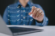 © Nirusmee - Hand using pen to check virtual checklist on laptop, representing task management, digital workflow, productivity, project planning, and online organization system.