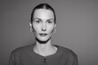 © SHOTPRIME STUDIO - Portrait of a serious white woman in her thirties with light skin and slicked back hair wearing a textured jacket against a plain background.