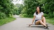 © Таня Андреева - Happy Asian woman sitting on skateboard on park path in summer.