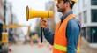 © ArtSync Studio - Construction Worker in Orange Safety Vest Communicating with Megaphone on Site