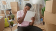 © Krakenimages.com - Man holding document with hand to cheek sitting amid packed boxes and ladder in a building; stress uncertainty.