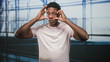 © Krakenimages.com - Black man pulls down lower eyelids with fingers and rolls eyes in airport terminal wearing pink tshirt and looking upward; tired travel delay.