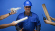 © Krakenimages.com - Man construction worker grimacing as hands present drone, walkie and rolled plans toward him in studio; teamwork frustration.