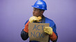 © Krakenimages.com - Man construction worker holds cardboard sign reading act now and presses ear protection to neck in studio; climate action urgent.