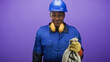 © Krakenimages.com - Construction worker holds money bag with dollar symbol and smiles wearing blue hardhat and yellow gloves in studio; prosperity pride.