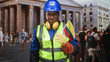 © Krakenimages.com - Man construction worker wearing blue hardhat and yellow vest holds colombia flag with gloved hand and frowns in building; disgust.