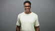 © Krakenimages.com - Man adjusts glasses and smiles, wearing a cream t shirt and round frames while facing the camera against a gray studio backdrop; friendly joy.
