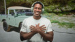 © Krakenimages.com - Man wearing headphones, hands crossed over chest gesture in forest next to vintage truck on dirt road, smiling with eyes closed; joy gratitude.
