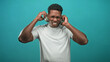 © Krakenimages.com - Man adjusting overear headphones with hands, eyes closed and smiling, wearing tshirt against teal studio set; pure joy.