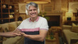© Krakenimages.com - Man wearing white headphones smiling and gesturing with open hand in a cozy living room inside a building; comfort relaxation leisure.
