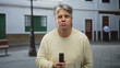 © Krakenimages.com - Man holding remote control, hand visible, smiling while standing on street in front of building; contentment.