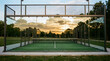 © Tromistudio  - Padel court with glass walls and metal fence at sunset or sunrise in a park with trees and green grass