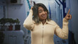 © Krakenimages.com - Woman points finger upward while touching her hair in a narrow street with white stairs and potted plants; playfulness curiosity.