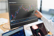 © Studio Marmellata - A person analyzes financial charts on a computer screen, with multiple devices displaying market data, indicating a focus on trading and investment strategies.