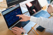 © Studio Marmellata - A person's hands are shown analyzing financial charts on multiple laptop screens, indicating a focus on trading and investment strategies.