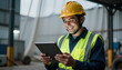 © NAD SANG PAP - Construction worker safety helmet tablet computer reflective vest smiling worker industrial warehouse maintenance check digital inspection male technician safety gear