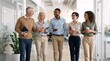© Vasiliy - Diverse business team walking and talking in a modern office hallway. Cheerful group of multiethnic colleagues holding coffee and notebooks during a collaborative discussion