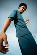© Maskot - Side view of young man with curly hair dancing near wall