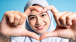 © Frame Stocks - Smiling woman forms a heart shape with her fingers, showing love and affection