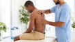 © Vera D - Professional male physiotherapist examining back of patient in clinic