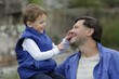 © atikinka2 - Close up of a father and young son smiling at each other during a playful bonding moment outdoors in a park.