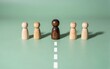 © joeycheung - Wooden figures stand in line one darker center figure leads the group.