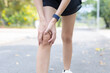 © Ratirat - Female runner holding her knee experiencing severe pain and physical discomfort after an outdoor injury stopping on road touching hurting leg joint showing suffering during an exercise routine